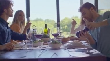 Bir grup mutlu arkadaş sohbet ediyor, yemek yiyor, şarap içiyor. İnsanlar modern ev partilerinin ya da öğle yemeğinin tadını çıkarıyor.