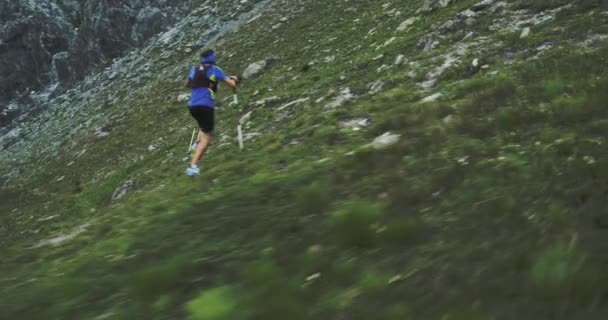 Dağ aveğinde koşan adam. Patika koşucusu kayalık tırmanışta en tepeye doğru koşuyor. Bulutlu sisli kötü havalarda vahşi yeşil doğa açık havada. Aktivite, spor, çaba, meydan okuma, irade kavramları — Stok video