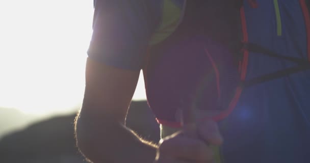 Trail runner man loopt het bereiken van Mountain Top Peak Goal uitziende horizon View. Arm schot. Wilde natuur buitenshuis bij zonsopgang of zonsondergang backlit. Trainingsactiviteit, sport, inspanning, uitdaging, wilskracht concept — Stockvideo