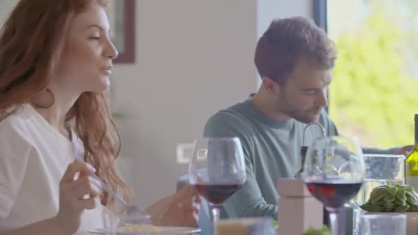 Група щасливих друзів, які спілкуються разом, їдять їжу, п'ють вино. — стокове відео