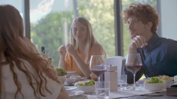 Grupo de amigos felices hablando juntos, comiendo, bebiendo vino.El grupo de personas disfruta de la cena o el almuerzo caseros modernos. — Vídeo de stock