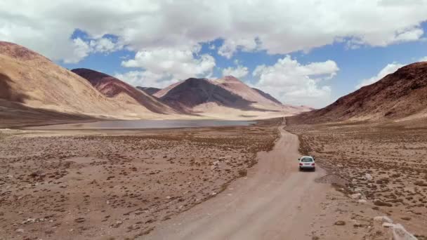 Ar ao longo da estrada 4x4 carro dirigindo ao longo da trilha de cascalho caminho perto de montanhas áridas do deserto. Pamir Rodovia seda viagem aventura estrada no Quirguistão e deserto do Tajiquistão, Ásia central.4k vídeo de voo drone — Vídeo de Stock