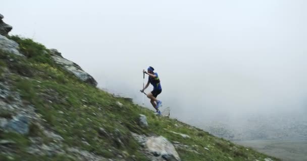 Hombre escalada correr en subida de montaña.Trail runner running to top peak training on rocky climb.Naturaleza verde salvaje al aire libre en el mal tiempo nublado niebla. Actividad, deporte, esfuerzo, desafío, conceptos de fuerza de voluntad — Vídeos de Stock