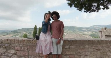 Romantik Çift kırsal kasaba, Assisi.approach içinde geniş bir selfie ile smartphone alarak vurdu. Arkadaşlar Umbria.4k yavaş çekimde İtalyan yolculuk