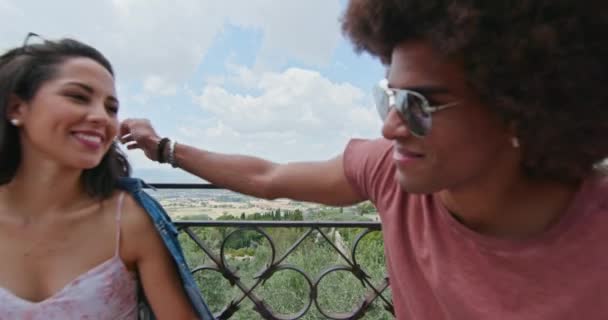 Romantiskt par sitter på bänken pratar känsla gratis och glad till det stora torget i landsbygdens stad Assisi. tillbaka avlägsnande. Vänner italiensk resa i Umbrien. 4K slow motion — Stockvideo