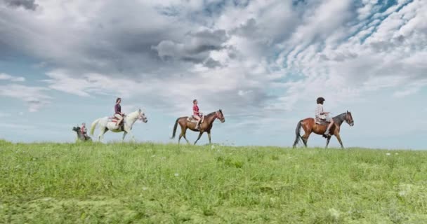 四个活跃的人骑着马在阳光明媚的户外野生绿色户外场。侧跟随宽镜头。朋友意大利之旅在翁布里亚.4k慢动作 — 图库视频影像