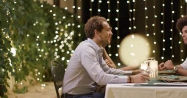 Dört kişi, romantik bir gurme toplama akşam yemeği veya öğle yemeği sırasında yeme ve içme konuşurken mutlu iki çift. Parlak ışıklandırma. Orta atış. Umbria.4k yavaş hareket Arkadaşlar İtalyan gezisi