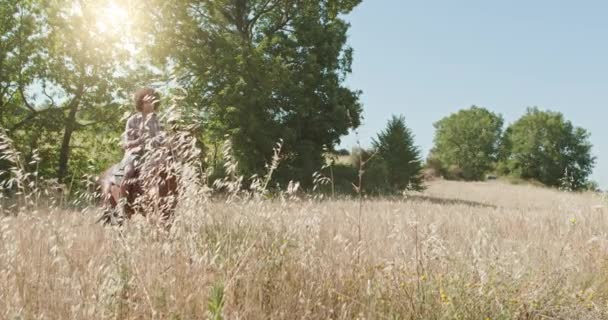 Homem montando cavalos em um campo selvagem ao ar livre ensolarado.Amigos viagem italiana em Umbria.4k câmera lenta — Vídeo de Stock