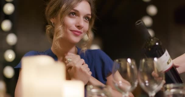 Serveur versant du vin rouge dans un verre pour femme pendant que les gens, parlant, mangeant, buvant pendant le dîner ou le déjeuner de rassemblement gastronomique romantique.Éclairage brillant. Amis voyage italien en Ombrie 4k slow motion — Video