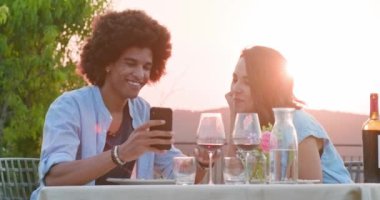 Gün batımında romantik açık hava yemeği sırasında selfie çeken akıllı telefon cihazı nı kullanan erkek ans kadın. Umbria.4k yavaş hareket Arkadaşlar İtalyan gezisi