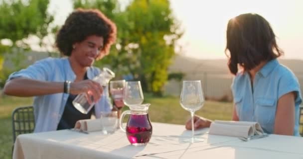 Manželé rádi mluví, jedí a pijí během romantické labužnické večeře venku při západu slunce. Střední záběr, podsvícení. Italský výlet v Umbrii. 4k pomalý pohyb — Stock video
