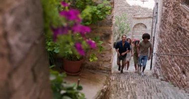 Dört mutlu turist yürüyüş ve Spello.Front kırsal kasaba ziyaret küçük sokak merdivenlerinden çalışan izleyin. Umbria Arkadaşlar İtalyan tatil gezisi.4k yavaş hareket
