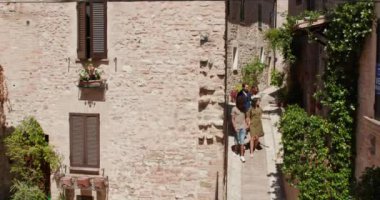 Dört mutlu turist yürüyüş ve Spello.Front görünümü kırsal kasaba ziyaret küçük bir sokak ile hayran çalışan. Umbria Arkadaşlar İtalyan tatil gezisi.4k yavaş hareket