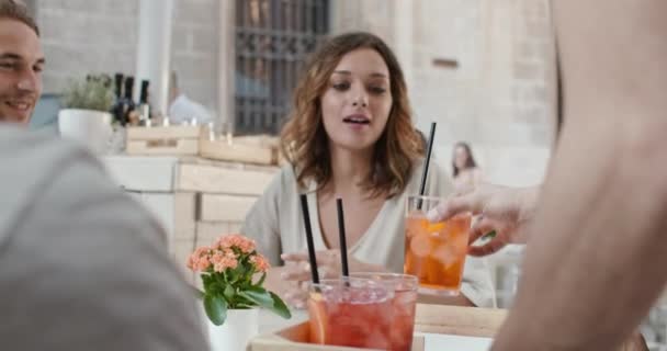 Servitör ger cocktails till fyra personer eller två par på aperitif i City Café. Medium porträtt shot vänner italiensk resa i Umbrien. 4K slow motion — Stockvideo