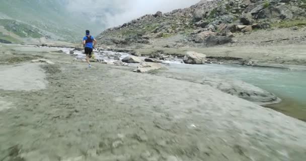 Man running near mountain creek river.Trail runner run to top peak training on rocky climb.Wild green nature outdoors in cloudy foggy bad weather. Activity,sport,effort,challenge,willpower concepts — Stock Video