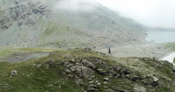 Aérea del hombre corriendo en subida de montaña.Corredor de sendero corriendo a la cima del entrenamiento pico en escalada rocosa.Naturaleza verde salvaje al aire libre en el mal tiempo nublado niebla. Actividad, deporte, esfuerzo, desafío, fuerza de voluntad . — Vídeo de stock