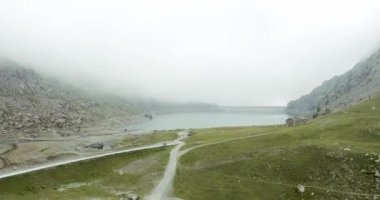 Baraj yapay göl yakınında tırmanma İtalyan Alpleri dağ riff üzerinde havadan kurma uçuş. Sisli veya bulutlu havalarda vahşi yeşil doğa açık havada. 4k drone kamyon üzerinde