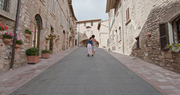 Romantic couple walking visiting rural town of Assisi.Back follow.Friends italian trip in Umbria.4k slow motion.