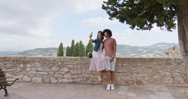 Romantyczna para biorąc selfie z smartphone w wiejskich miasta Assisi.approach szeroki strzał. Przyjaciele włoskiej podróży w Umbria.4k zwolnionym tempie — Zdjęcie stockowe