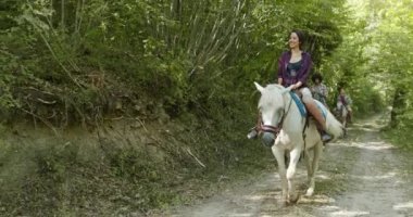 Güneşli bir açık orman tarlasında ata binen dört aktif insan. Umbria.4k yavaş hareket Arkadaşlar İtalyan gezisi