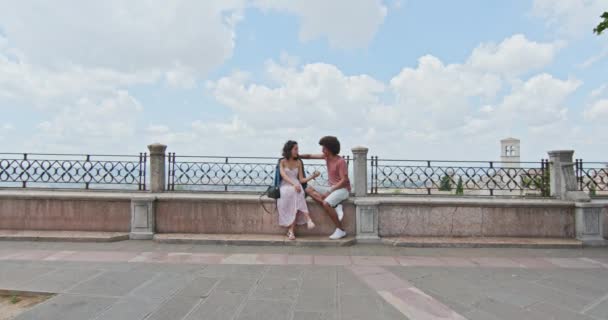 Pareja romántica sentada en el banco hablando sintiéndose libre y feliz de la plaza principal en la ciudad rural de Assi.Approaching.Friends viaje italiano en Umbria.4k cámara lenta — Vídeo de stock