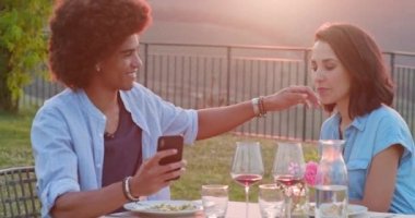Gün batımında romantik açık hava yemeği sırasında selfie çeken akıllı telefon cihazı nı kullanan erkek ans kadın. Umbria.4k yavaş hareket Arkadaşlar İtalyan gezisi