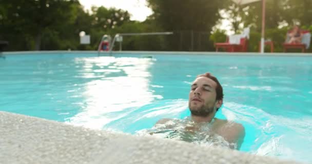L'uomo in acqua si rilassa in piscina nella giornata di sole.Amici viaggio italiano in Umbria.4k slow motion — Video Stock