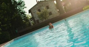 Güneşli bir günde yüzme havuzunda dinlenen kadın suya. Umbria.4k yavaş hareket Arkadaşlar İtalyan gezisi
