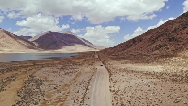 Aerial over off road 4x4 car driving along gravel trail path near arid desert mountains.Pamir Highway silk road trip aventure au Kirghizistan et dans le désert du Tadjikistan, Asie Centrale 4k drone flight video — Video