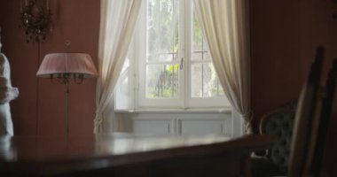 Yaşlı büyükanne kadın pencerenin yanında dışarı yada bakıyor. Evde güzel beyaz saç yaşlı büyükanne.4k yavaş hareket video