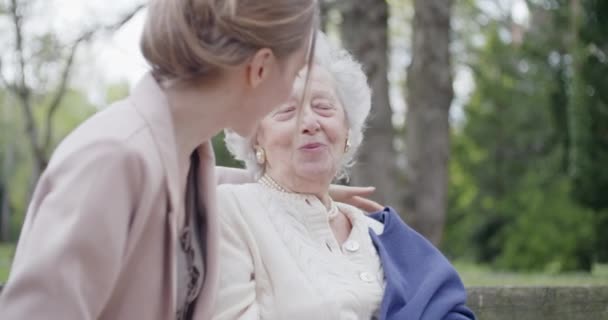 Farmor kvinna kysser och kramar barnbarn på City Park. Multigeneration kvinnor älskar att hålla ihop. Vitt hår äldre mormor. Tillgivenhet, samhörighet, omsorg, kärleksfull, besök, pensionering — Stockvideo