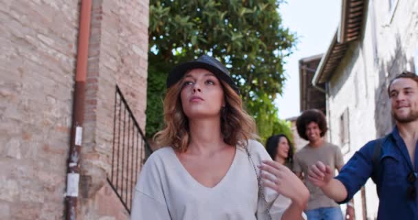 Člověk bere klobouk od ženské hlavy, aby jí zahrál vtip. Hravé přítelkyně žerty a procházky. Mladí a šťastní turisté cestují. Pohled zepředu. — Stock video