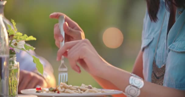 Detalle de la mano de la mujer comiendo pasta de espaguetis linguine con tenedor durante la cena gourmet romántica al aire libre al atardecer. Amigos viaje italiano en Umbria.4k cámara lenta — Vídeo de stock