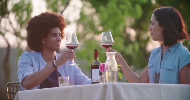 Hombre y mujer tostando y bebiendo vino tinto durante la cena gourmet romántica al aire libre al atardecer. Amigos viaje italiano en Umbria.4k cámara lenta — Vídeos de Stock