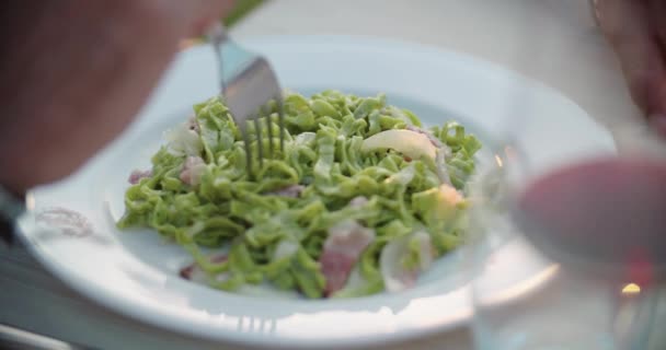 Hombre detalle de la mano comer pasta de espaguetis linguine con tenedor durante la cena gourmet romántica al aire libre al atardecer. Amigos viaje italiano en Umbria.4k cámara lenta — Vídeo de stock