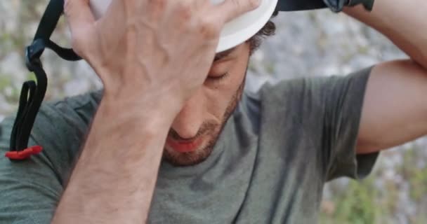 Homem alpinista se preparando para subir a fenda da parede rochosa, colocando capacete. Escalada atividade esportiva ativa extrema. Pessoas activas, actividades ao ar livre. Detalhe da cabeça da frente.Vídeo em câmera lenta 4k . — Vídeo de Stock