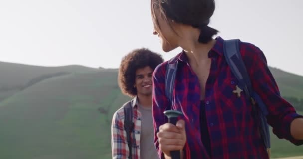 Muž a žena turistika pomocí trekking tyče.Nordic chůze venku na stezce poblíž květinových polí v Castelluccio di Norcia.Friends italský výlet v Umbrii za slunečného denu.Zpomalení pohybu 60 fps handheld — Stock video