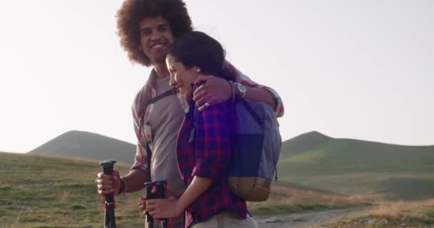 Dos personas pareja en amor hombre y mujer mirando paisaje panorama.Hiking con bastones de trekking o nordic caminar al aire libre en un sendero al atardecer o al amanecer. — Vídeo de stock