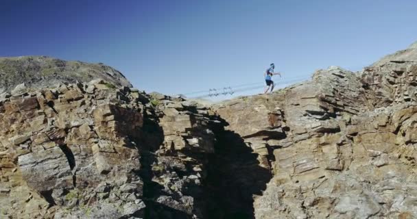 Aerial of man run on ridge edge.Trail runner running to mountain top peak training on rocky cliff.Wild green nature outdoor at sunrise or sunset backlit. Atividade, esporte, esforço, desafio, força de vontade — Vídeo de Stock