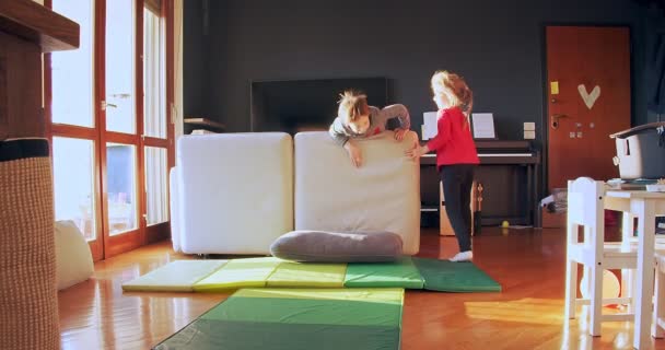 Zwei Kinder spielen zu Hause zusammen. Bruder und Schwester spielen drinnen. Vorderansicht mittlerer Schuss. Kinder spielen zusammen im Wohnzimmer. Zeitlupe — Stockvideo