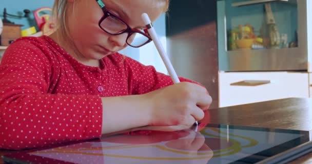 Meisje tekent thuis op tablet. Kindertekening op tabletapparaat in de keuken op afstand. Meisje maakt huiswerk op tablet. Slimme opleiding. Thuis naar school. Afstandsonderwijs — Stockvideo