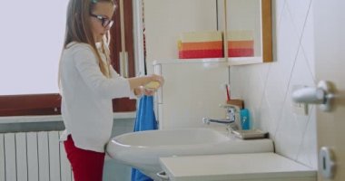 Küçük kız evde sabunla ellerini dikkatlice yıkıyor. Orta ölçekli. Çocuk ellerini sabun banyosuyla yıkıyor. El hijyeni..