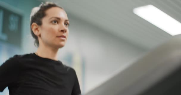 Jeune femme courant sur un tapis roulant au gymnase. Vue de face rapprochée, détail du haut du corps. Entraînement de femme au centre de fitness. Femme faisant de l'exercice cardio 