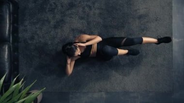 Evdeki zeminde egzersiz yapan bir kadının en iyi görüntüsü. Tepedeki kadın evde fitness antrenmanı yapıyor. Karın kaslarını çalıştıran kadın. Endüstriyel ev