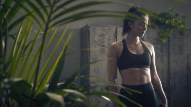 Kadın evde özel antrenör uygulaması olan akıllı telefon kullanıyor. Kadın spor yapmak için fitness uygulamasını kullanıyor. Yörüngeye yakın çekim. Kadın spor yaparken cep telefonu kullanıyor. 