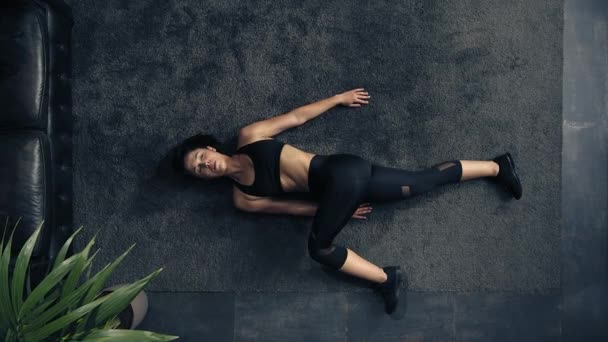 Vista superior de la mujer haciendo estiramiento en el suelo en casa. Mujer de arriba haciendo entrenamiento de fitness en casa. Mujer entrenando abdominales. Casa de estilo industrial — Vídeos de Stock