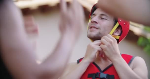 Man dragen van sport helm en zwemvesten voor rafting rivier afdaling.Groep van mensen briefing voor het starten van extreme sportactiviteit.Rafting extreme sport.zon achtergrondverlichting handheld. — Stockvideo