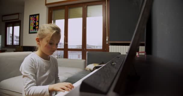 Niña tocando el piano en casa. El chico toca el piano en la sala. Niño aprendiendo piano en casa. Lección de música, vista frontal de plano medio . — Vídeos de Stock