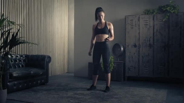 Mujer que utiliza el teléfono inteligente con la aplicación de entrenamiento entrenador personal en casa. Mujer preparándose para el entrenamiento con la aplicación de fitness. Disparo de órbita completa.Mujer usando teléfono móvil mientras descansa durante el entrenamiento físico — Vídeo de stock