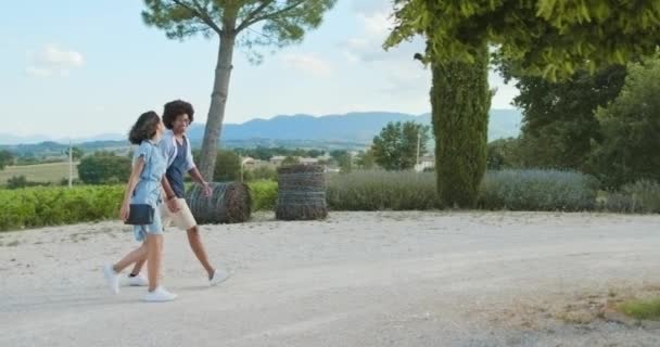 Couple romantique, homme et femme marchant dans la cour avant de la maison de luxe pour déguster du vin rouge et manger de l'apéritif au coucher du soleil chaud.Plan moyen. Amis voyage italien en Ombrie 4k slow motion — Video